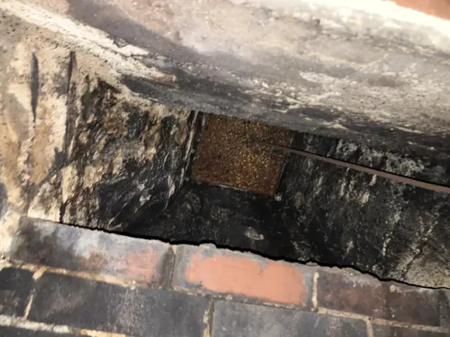 Sooty, rusted damper area inside a brick fireplace